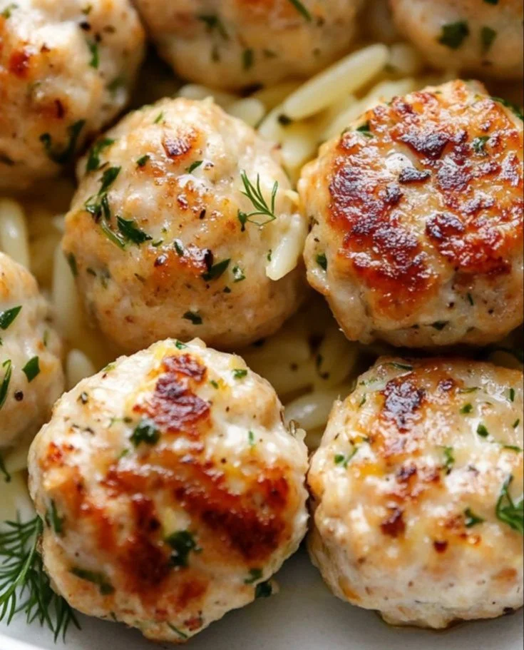 Plate of Greek chicken meatballs with lemon orzo garnished with herbs