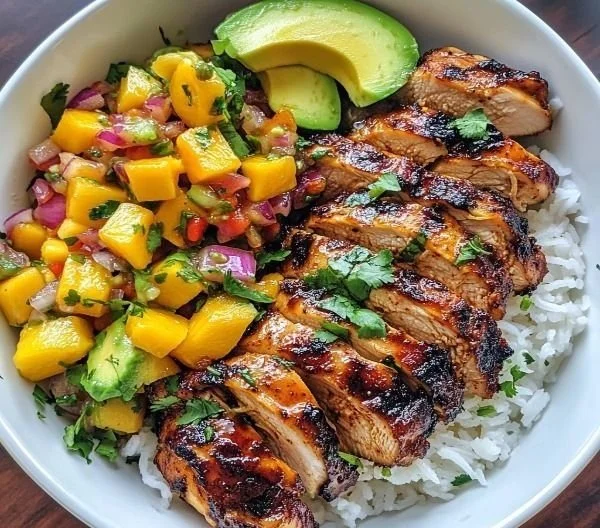 Jerk chicken bowl with mango salsa and coconut rice, garnished and ready to serve.