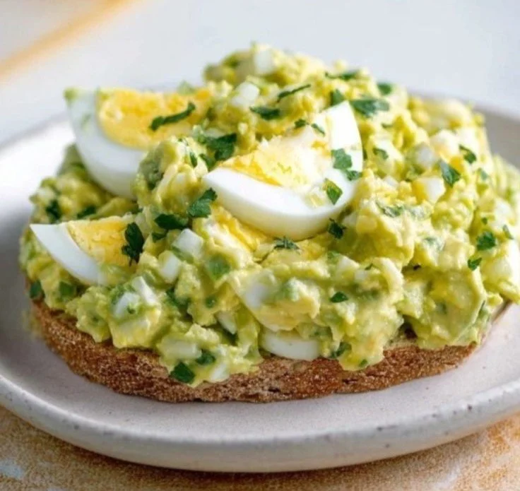Mediterranean avocado egg salad in a bowl garnished with herbs and spices