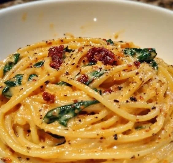 Spaghetti with spinach and sun-dried tomato cream sauce served in a bowl