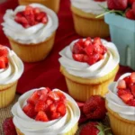 Delicious strawberry shortcake cupcakes topped with whipped cream and fresh strawberries.