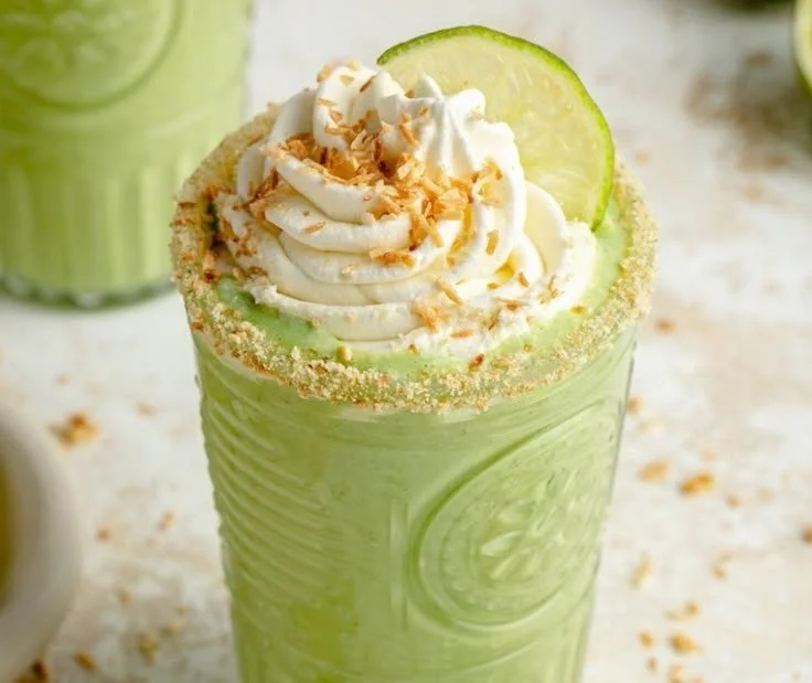 Creamy coconut key lime pie smoothie in a glass with lime and coconut toppings