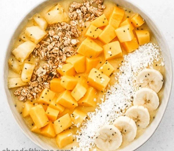 Mango Pineapple Tropical Smoothie Bowl topped with fresh fruits and granola