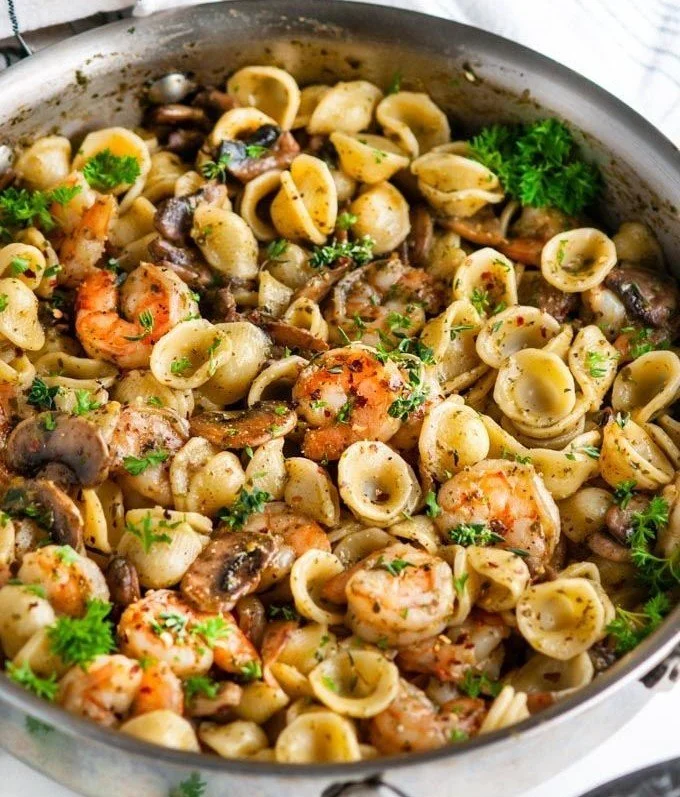 Delicious pesto shrimp pasta dish garnished with fresh basil and cherry tomatoes.