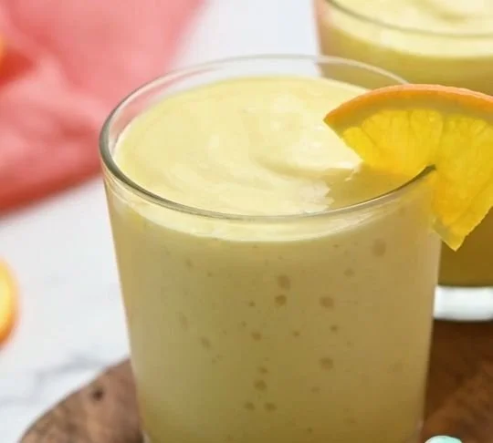 Simple mango smoothie in a glass with fresh mango slices