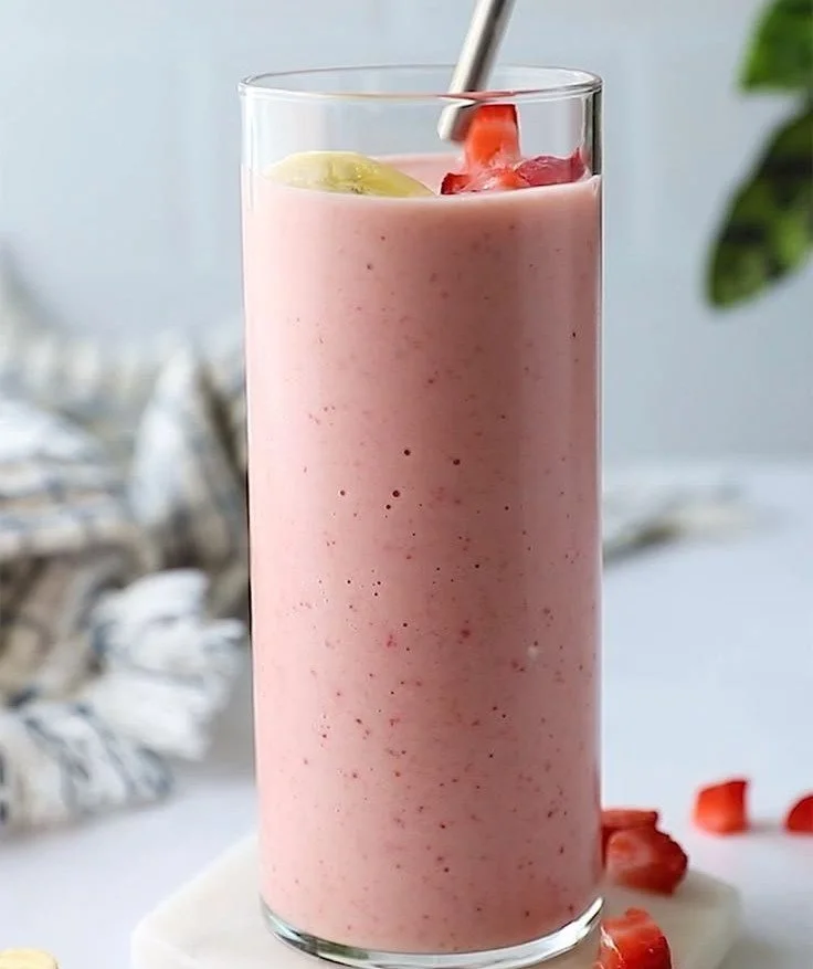 Delicious strawberry banana smoothie in a glass with fresh fruit garnishes.