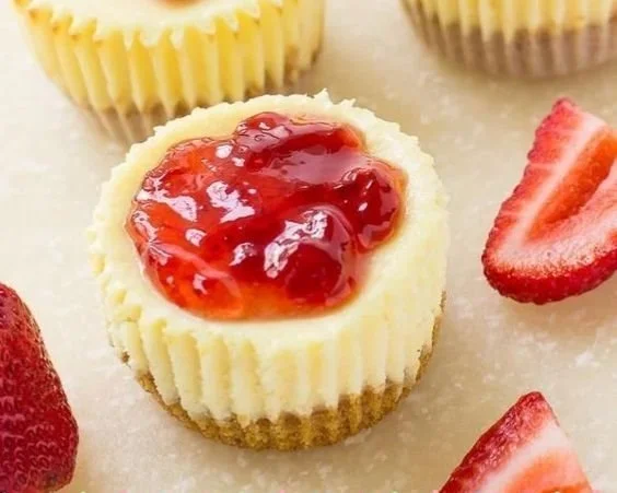 Strawberry cheesecake bites on a plate, topped with fresh strawberries.