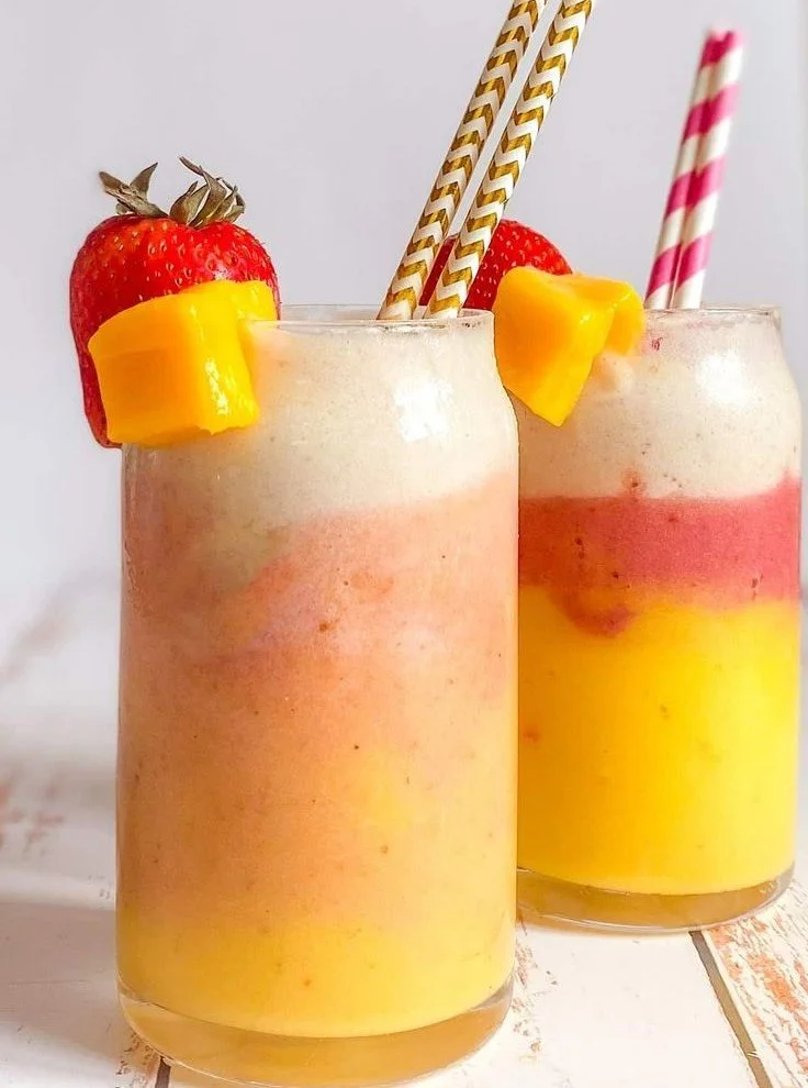 Tropical banana mango smoothie with strawberries in a glass
