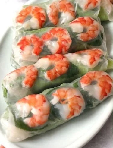 A plate of fresh Vietnamese spring rolls filled with herbs and vegetables
