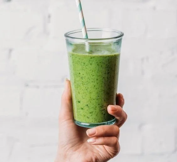 A vibrant spinach smoothie in a glass, garnished with fresh ingredients.