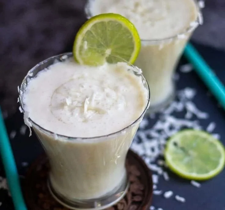 Delicious Coconut Limeade served in a glass with lime and coconut garnishes.