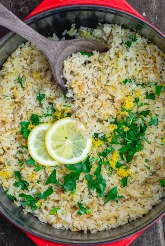 Bowl of Greek Lemon Rice topped with fresh herbs and lemon slices.