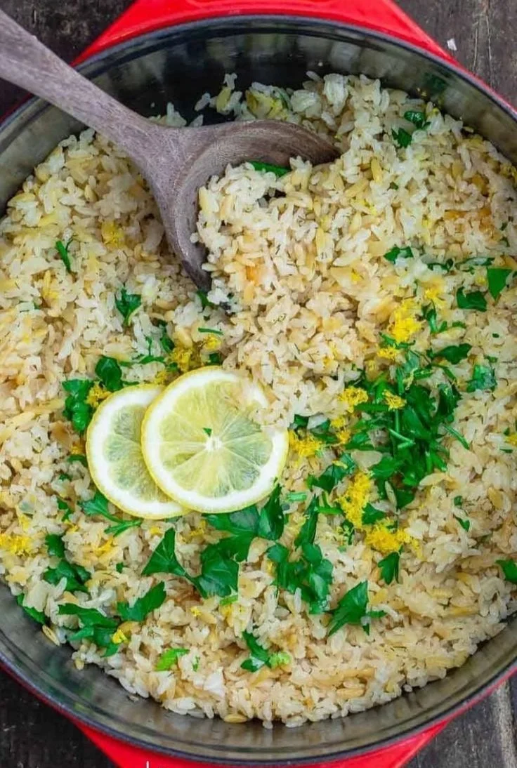 Bowl of Greek Lemon Rice topped with fresh herbs and lemon slices.