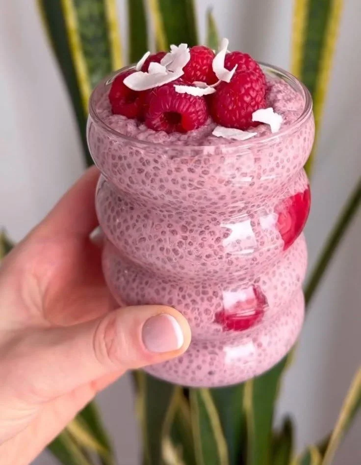 A bowl of creamy raspberry chia pudding topped with fresh raspberries and mint leaves