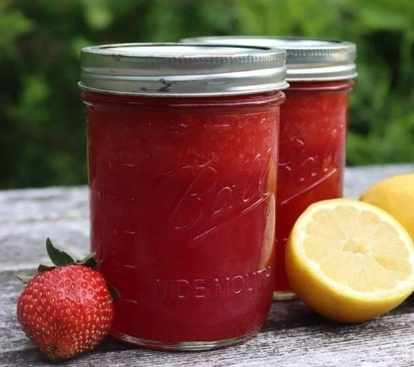 Homemade strawberry lemonade concentrate in a glass with fresh strawberries